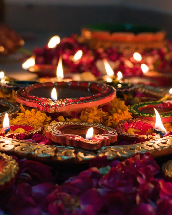 Lit clay lamps on a tray of flower petals
