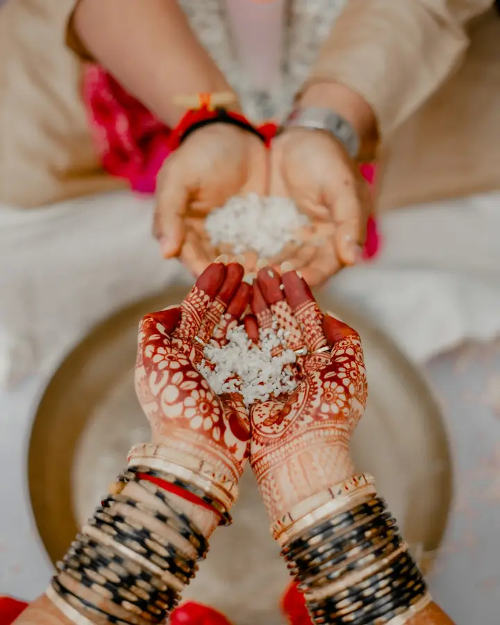 A bride's hennaed hands receiving rice at a wedding