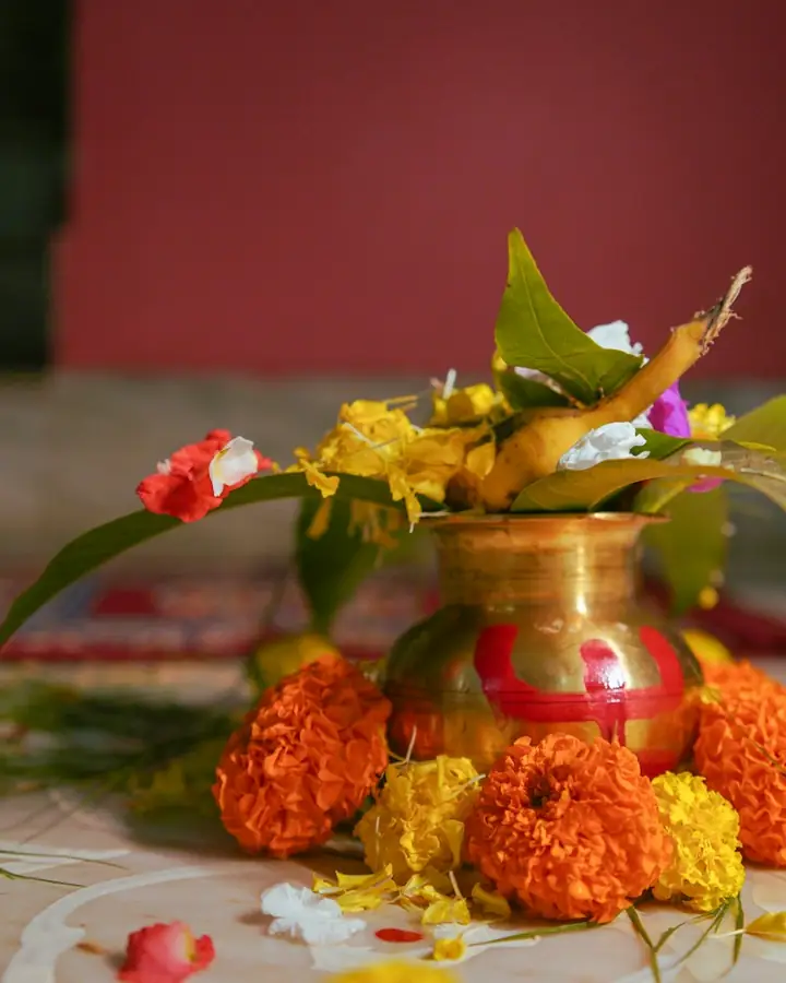 A brass kalash with mango leaves and marigolds